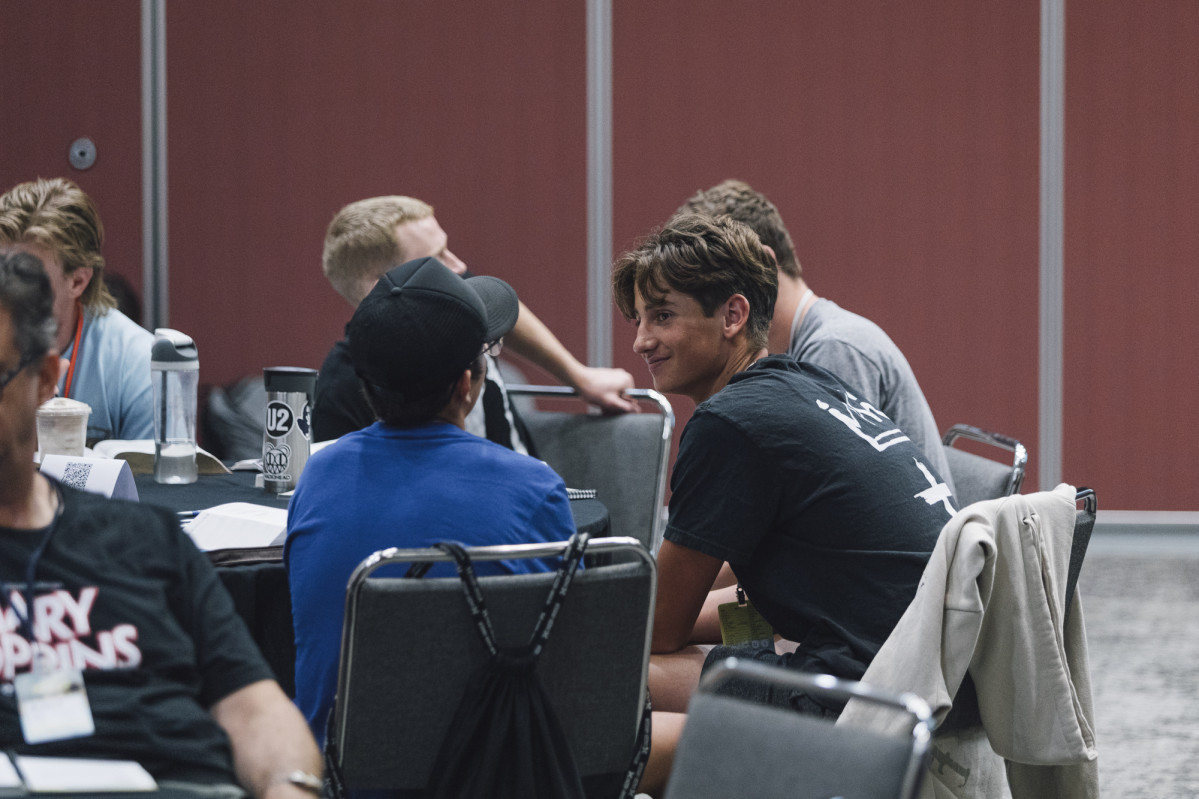 A teenage boy smiles at his friend sitting next to him